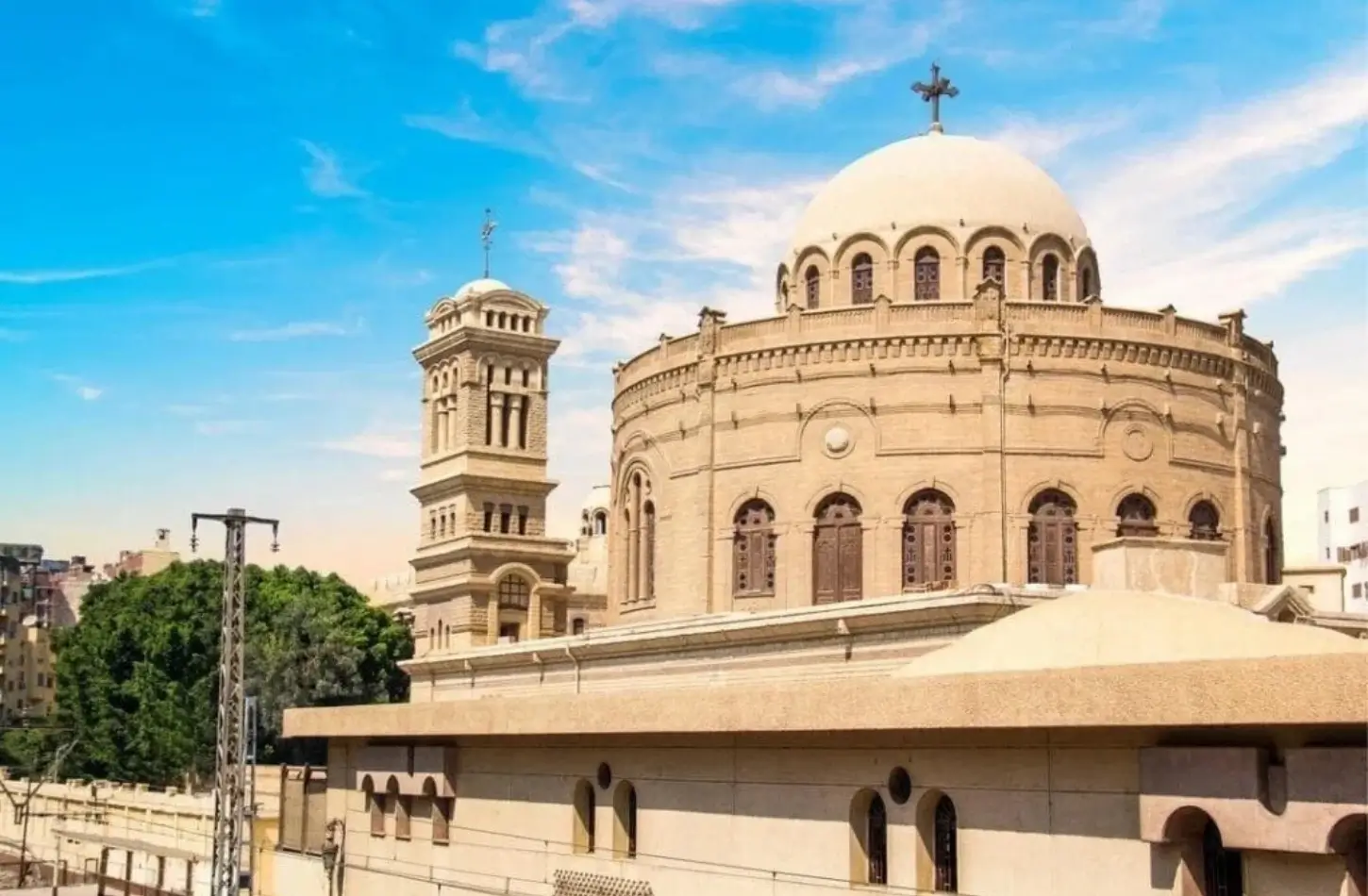 The stone dome and soaring bell tower of the historic Church of St. George in Coptic Cairo under a bright blue sky, featured on a day tour itinerary from Marsa Alam