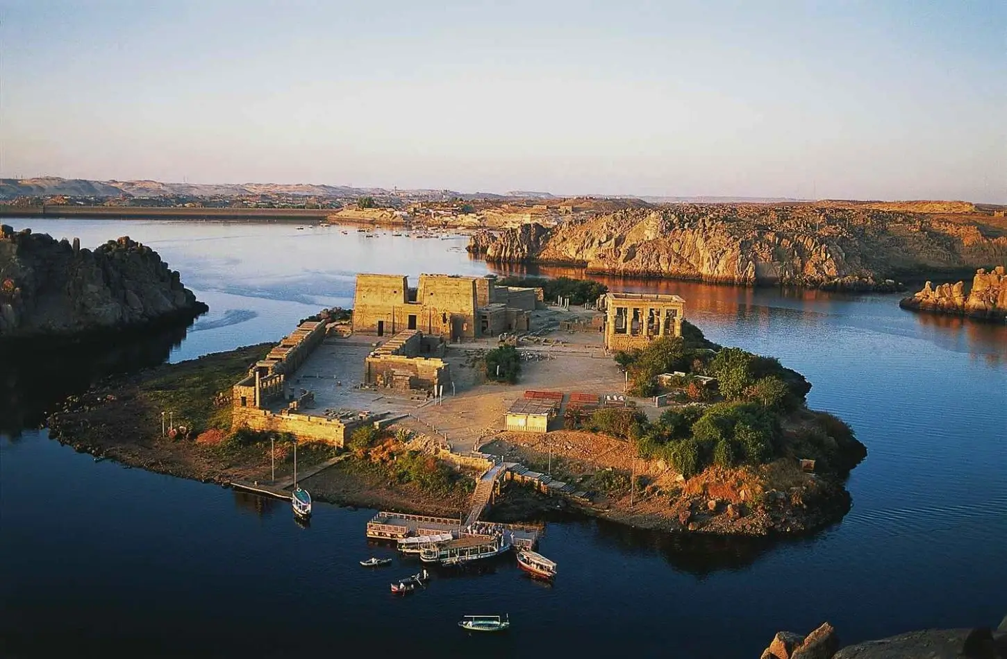 Ancient Egyptian philae temple complex on Agilkia Island in Aswan, featuring stone pylons, courtyards, and Trajan's Kiosk surrounded by the Nile River.