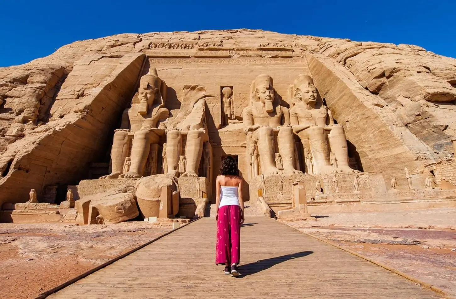 Sólo žena turista kráčející směrem k starobylým chrámům Abu Simbel, přemýšlející, zda je bezpečné cestovat do Egypta.